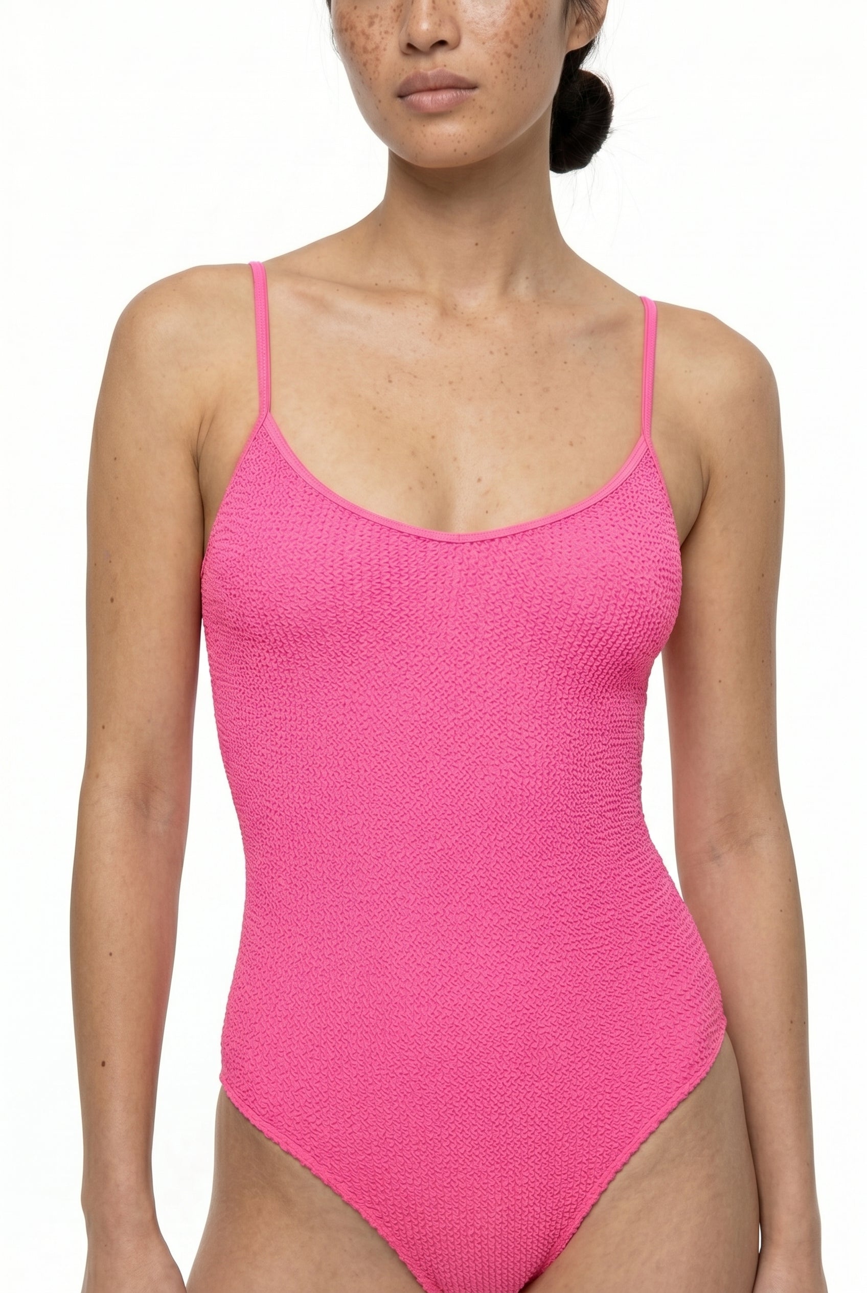 Woman wearing a pink textured swimsuit against a white background