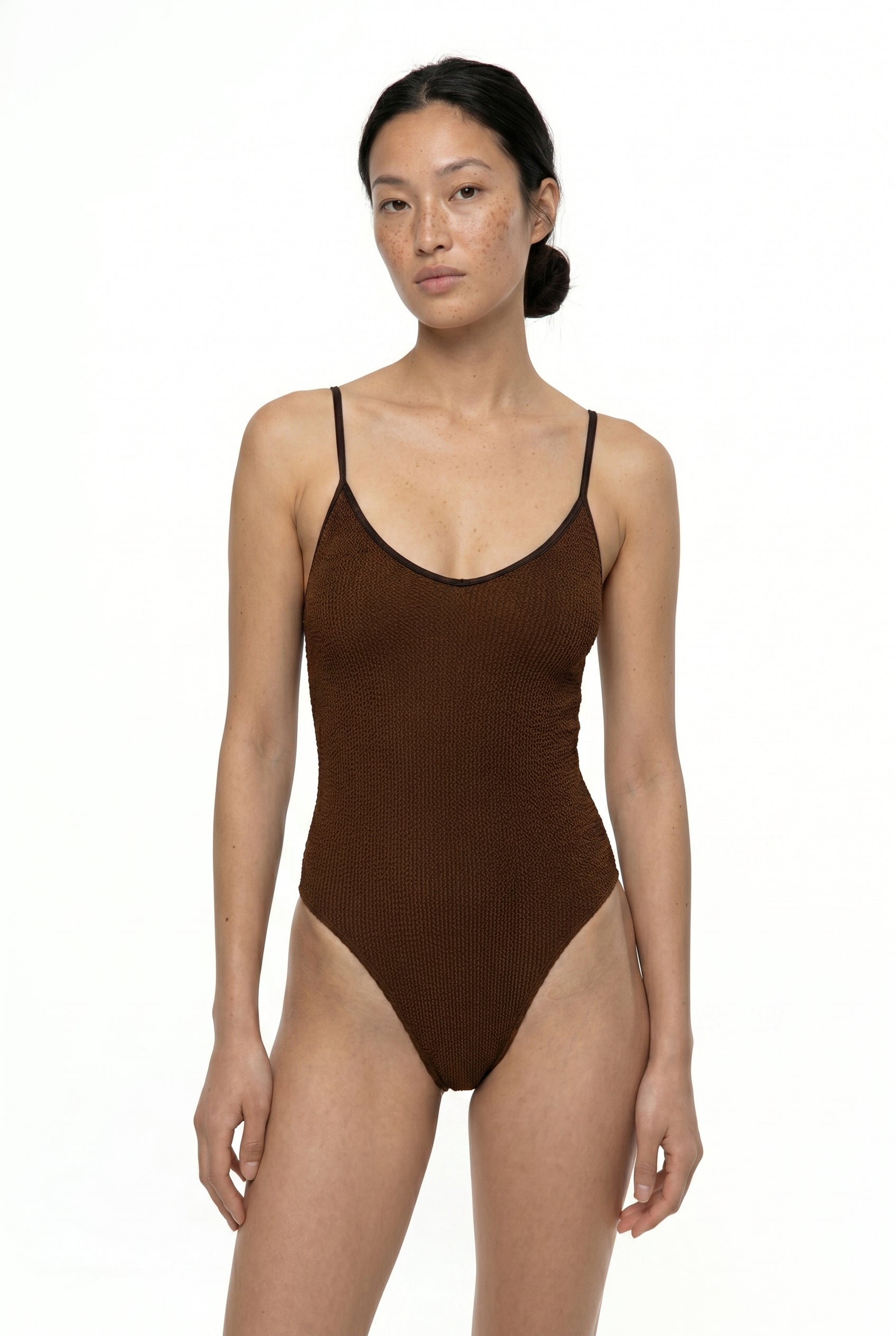 Woman wearing a brown swimsuit against a white background