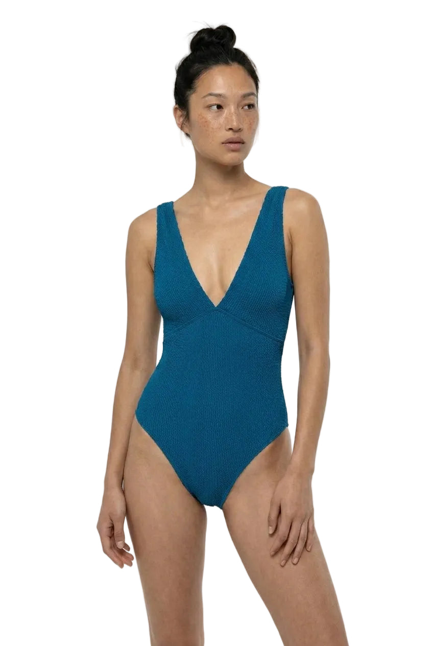 Woman wearing a teal swimsuit on a white background