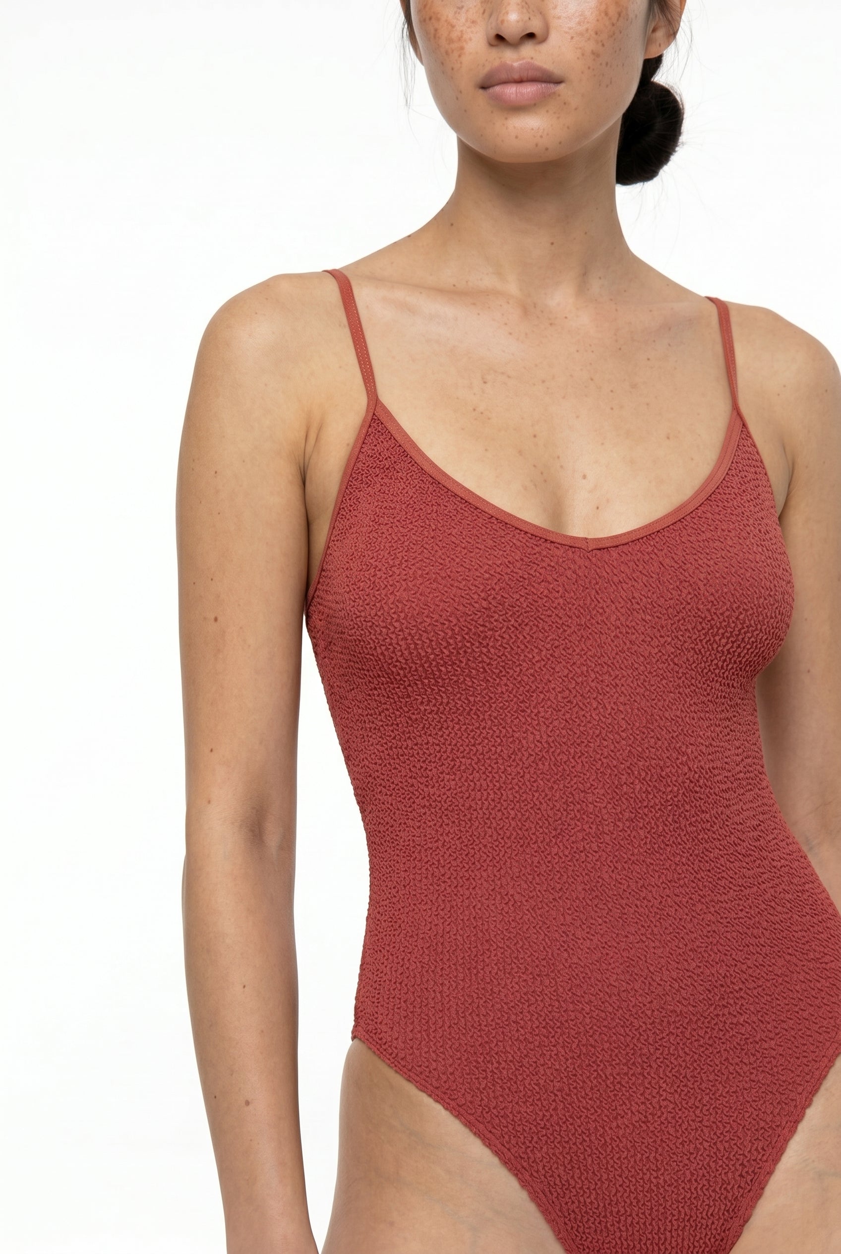 Red textured swimsuit worn by a model on a white background