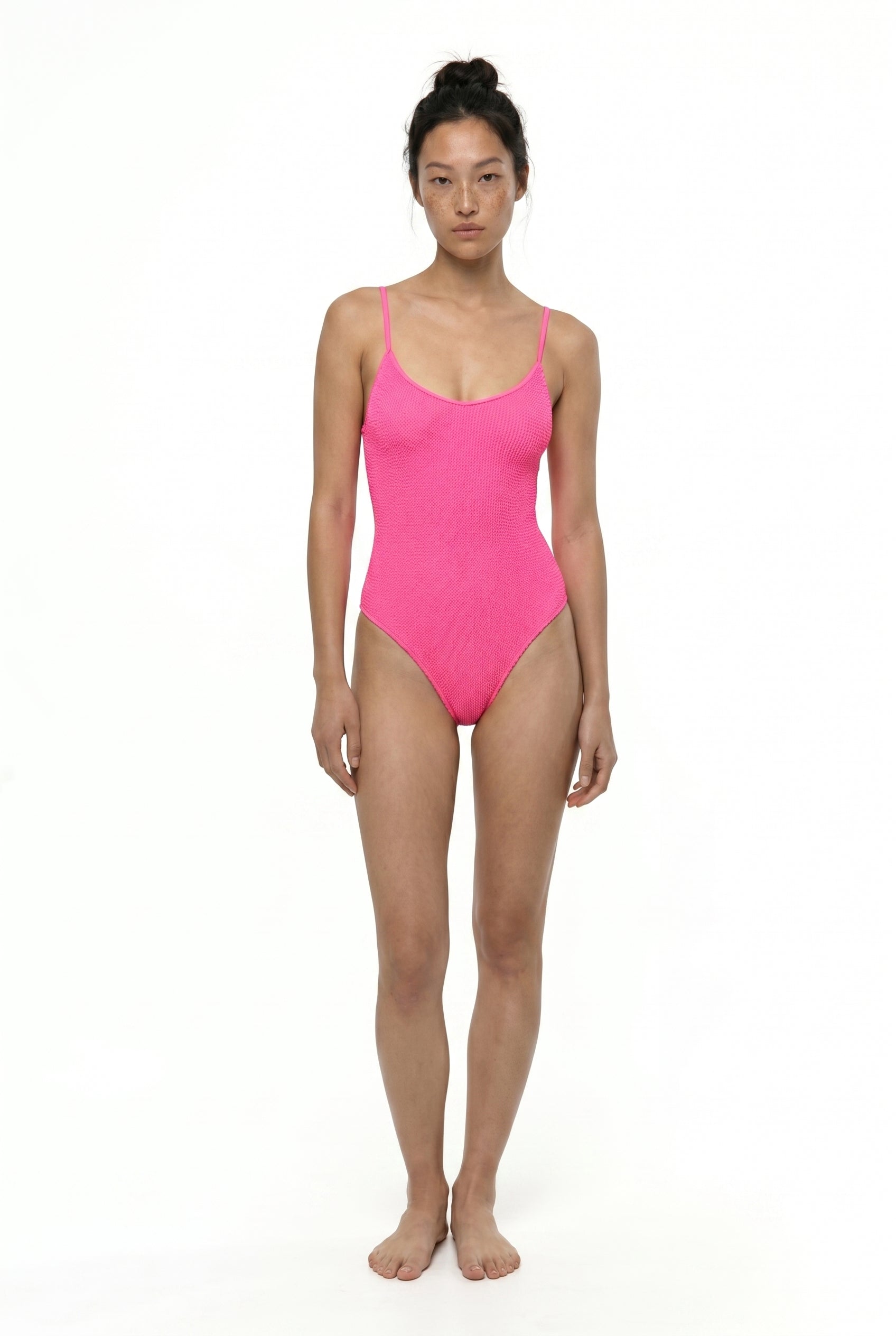 Woman wearing a bright pink swimsuit on a white background
