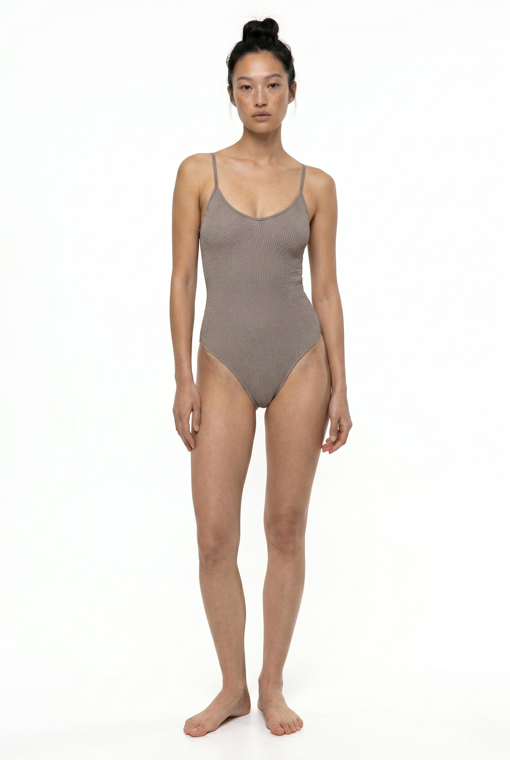 Woman wearing a brown swimsuit on a white background